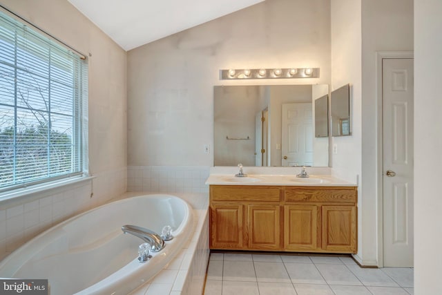 bathroom with tile patterned flooring, a garden tub, lofted ceiling, and a sink