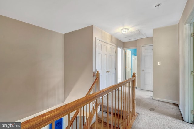 corridor featuring an upstairs landing, light colored carpet, and baseboards