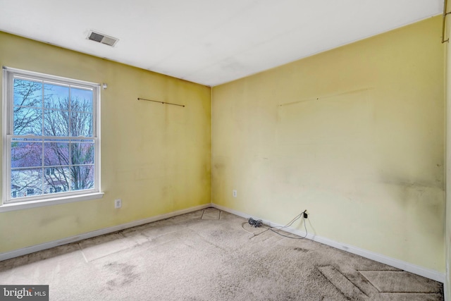 spare room featuring a wealth of natural light, visible vents, baseboards, and carpet flooring