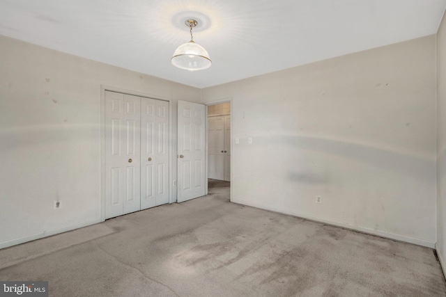 unfurnished bedroom featuring carpet flooring, baseboards, and a closet