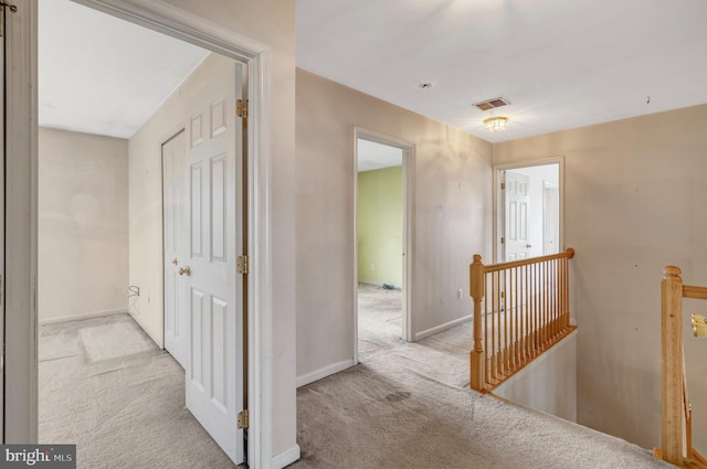 corridor featuring an upstairs landing, visible vents, carpet flooring, and baseboards