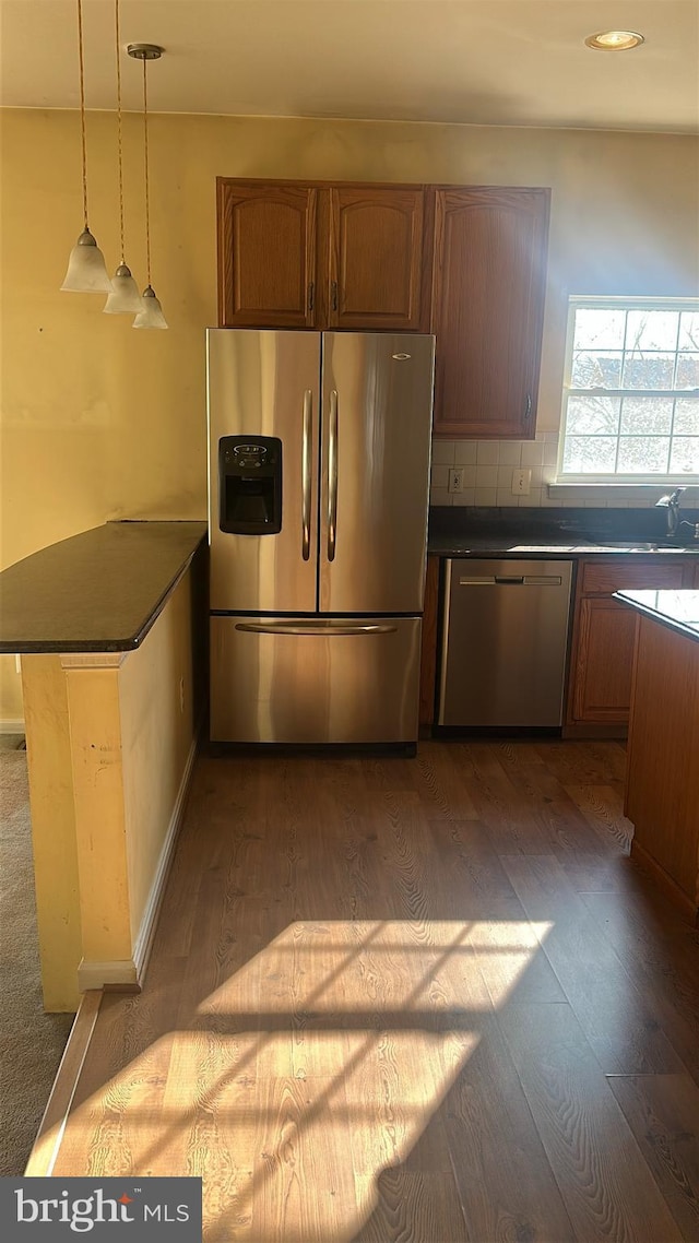 kitchen featuring dark countertops, appliances with stainless steel finishes, a peninsula, and dark wood-style flooring