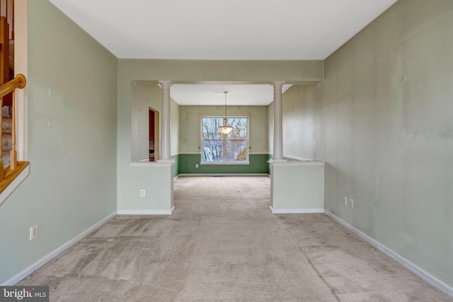 spare room with carpet floors, baseboards, and decorative columns