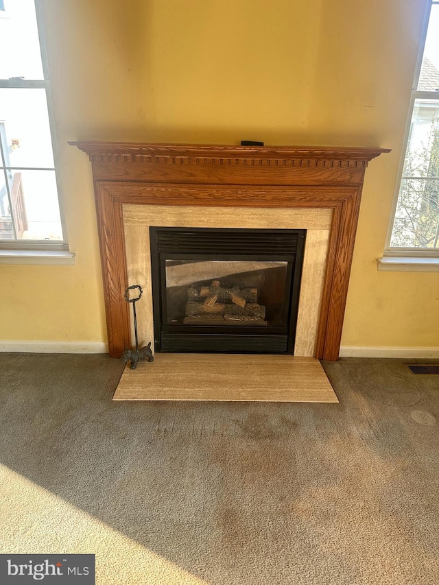 details with visible vents, carpet floors, baseboards, and a glass covered fireplace