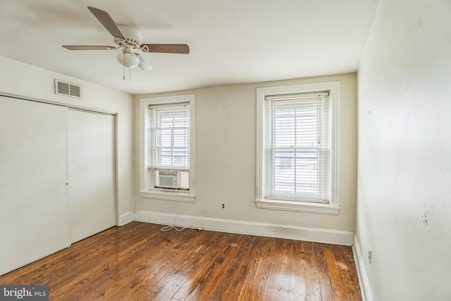 unfurnished bedroom featuring cooling unit, dark wood-type flooring, a closet, and ceiling fan