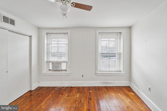 unfurnished bedroom featuring cooling unit, hardwood / wood-style flooring, a closet, and ceiling fan