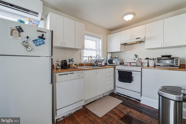 kitchen featuring white appliances, an AC wall unit, sink, and white cabinets