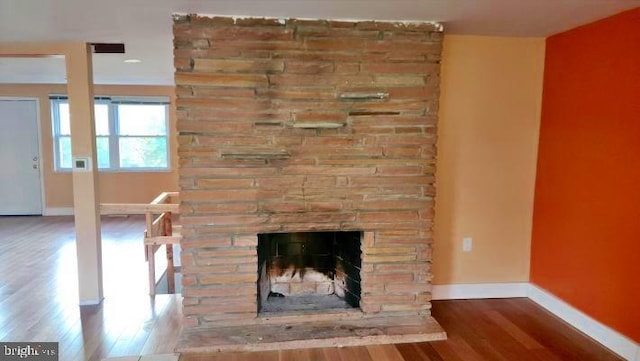 interior details with a stone fireplace and wood-type flooring