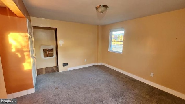 unfurnished room featuring dark colored carpet