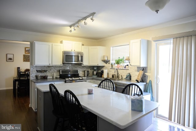 kitchen with crown molding, stainless steel appliances, white cabinets, and a kitchen island