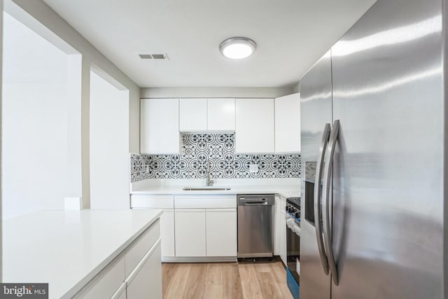 kitchen featuring stainless steel appliances, sink, white cabinets, and light hardwood / wood-style floors