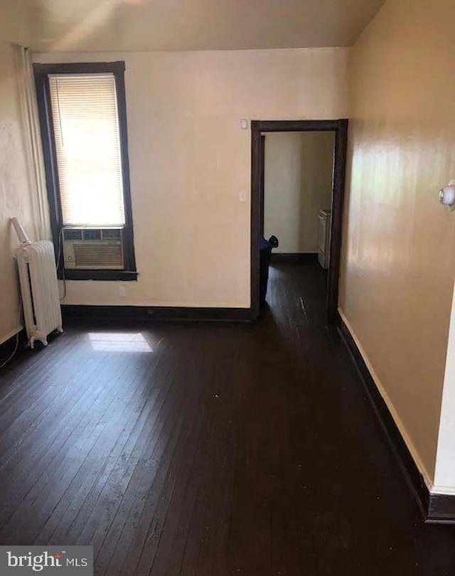 empty room featuring radiator heating unit and dark hardwood / wood-style floors