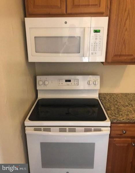 kitchen featuring white appliances and light stone countertops