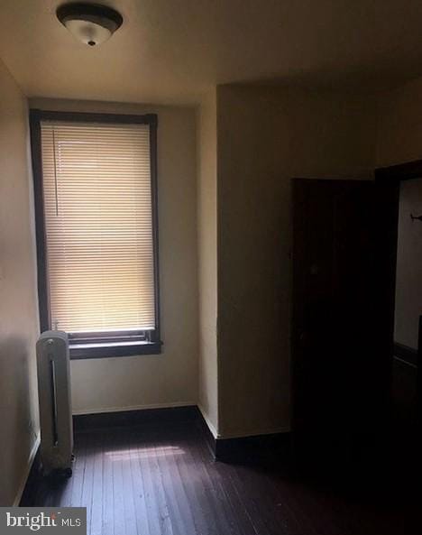 spare room with dark hardwood / wood-style flooring and radiator