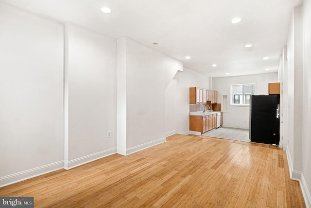 unfurnished living room with sink and light hardwood / wood-style floors