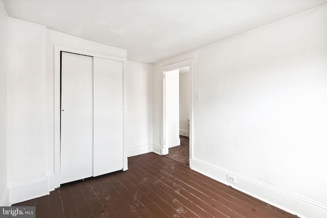 unfurnished bedroom with dark hardwood / wood-style flooring and a closet