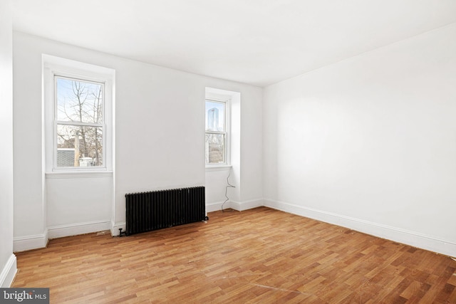 unfurnished room with radiator and light wood-type flooring