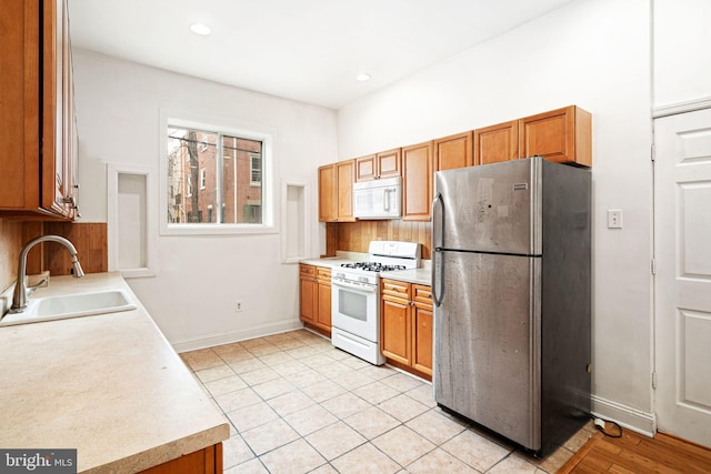 kitchen featuring sink, light tile patterned floors, and white appliances