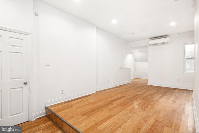 spare room featuring hardwood / wood-style floors and a wall unit AC