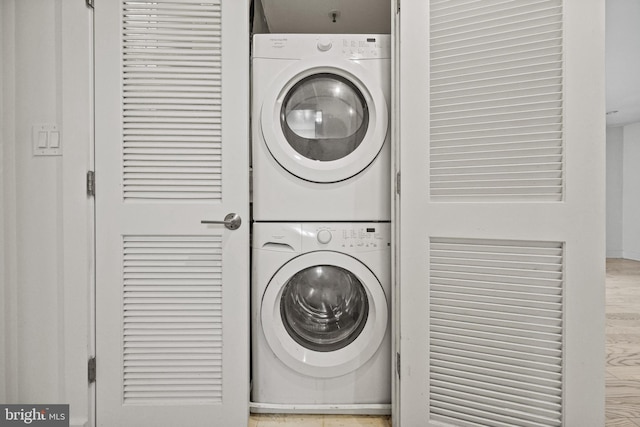 laundry room with stacked washer and dryer and light wood-type flooring