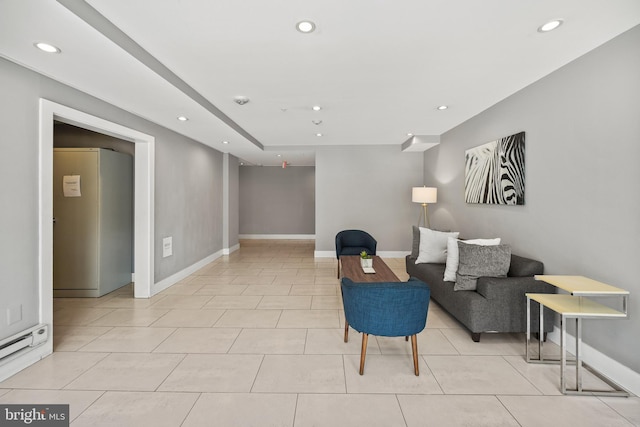 living area with a baseboard heating unit and light tile patterned floors