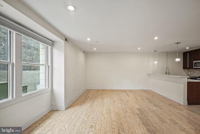 interior space featuring tasteful backsplash, dark brown cabinetry, light hardwood / wood-style floors, and hanging light fixtures