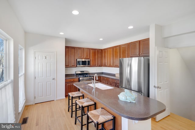 kitchen with sink, stainless steel appliances, a breakfast bar, and an island with sink