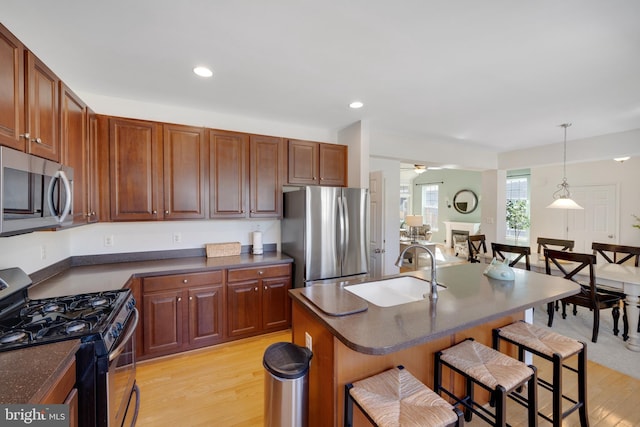 kitchen featuring sink, hanging light fixtures, a kitchen breakfast bar, stainless steel appliances, and a center island