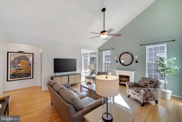 living room with light hardwood / wood-style flooring, high vaulted ceiling, and ceiling fan