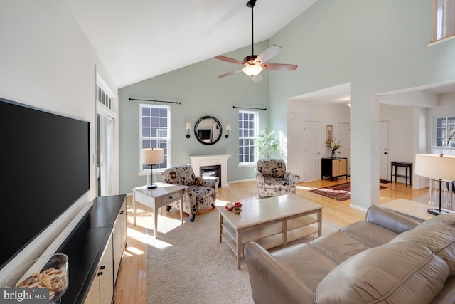 living room with high vaulted ceiling, ceiling fan, and light wood-type flooring