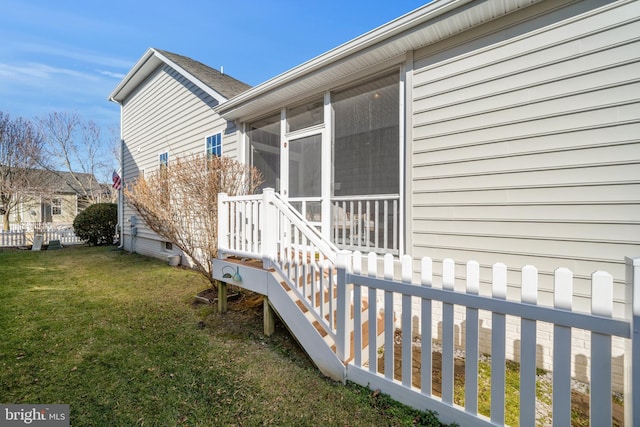 view of home's exterior featuring a sunroom and a lawn