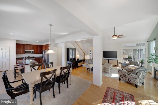 dining room with ceiling fan, vaulted ceiling, and light hardwood / wood-style flooring