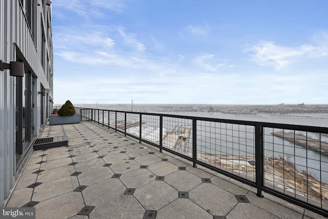 view of patio with a water view, a beach view, and a balcony