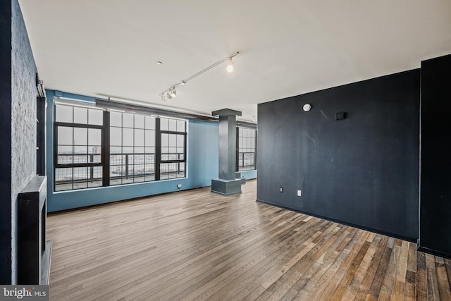 unfurnished living room with track lighting and wood finished floors