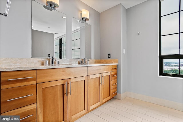 full bathroom featuring double vanity and baseboards