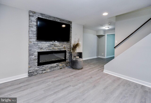 living area featuring baseboards, a fireplace, wood finished floors, and stairs