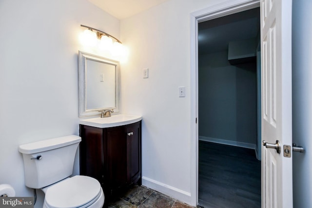 half bathroom with toilet, vanity, and baseboards