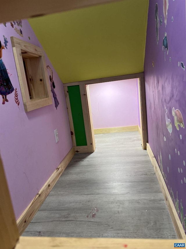 hallway featuring lofted ceiling and light wood-type flooring