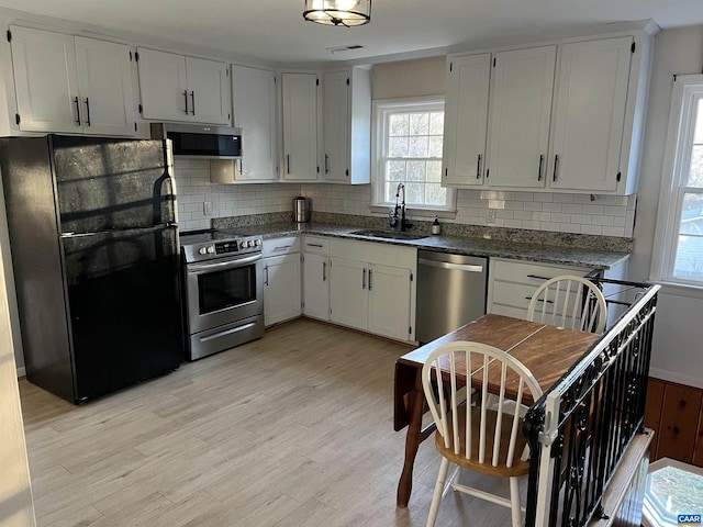 kitchen with appliances with stainless steel finishes, tasteful backsplash, white cabinetry, sink, and light hardwood / wood-style floors