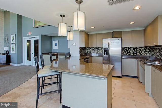 kitchen with dark stone countertops, light tile patterned floors, visible vents, a peninsula, and stainless steel fridge with ice dispenser