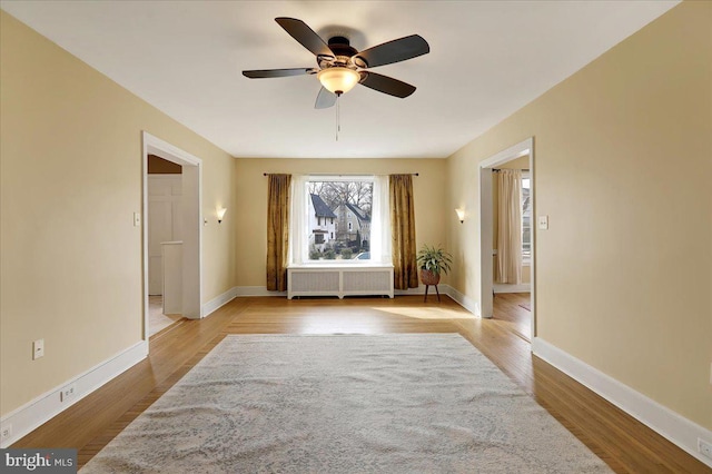 spare room with radiator, ceiling fan, and light wood-type flooring