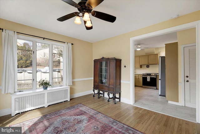 interior space with ceiling fan, radiator, and light hardwood / wood-style flooring