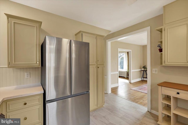 kitchen with stainless steel refrigerator, light hardwood / wood-style floors, and cream cabinetry