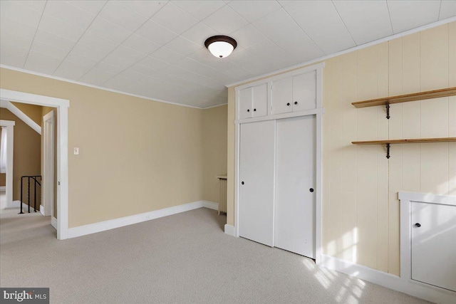 unfurnished bedroom with crown molding, a closet, and light carpet