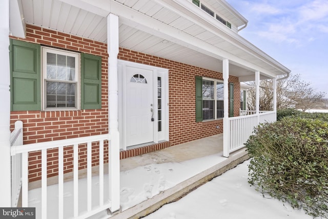 snow covered property entrance featuring covered porch