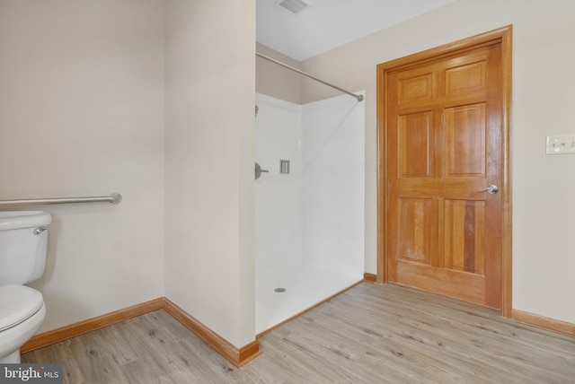 bathroom with hardwood / wood-style flooring, a shower, and toilet