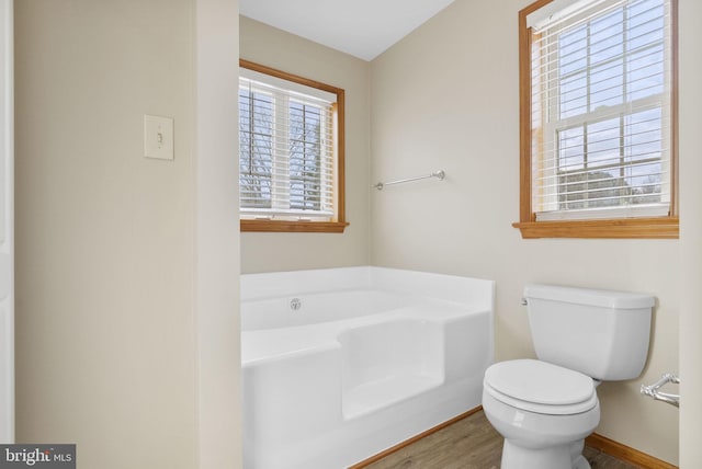 bathroom featuring wood-type flooring, a bath, and toilet