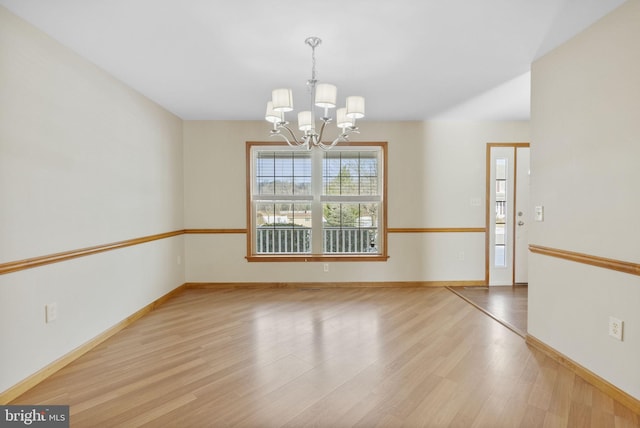 spare room featuring light wood-type flooring and an inviting chandelier