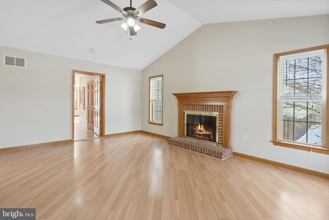 unfurnished living room with a fireplace, a wealth of natural light, light hardwood / wood-style floors, and vaulted ceiling