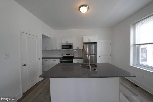 kitchen featuring sink, appliances with stainless steel finishes, a kitchen island with sink, white cabinets, and decorative backsplash